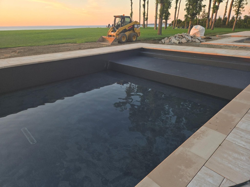 New pool construction overlooking a waterfront property at sunset