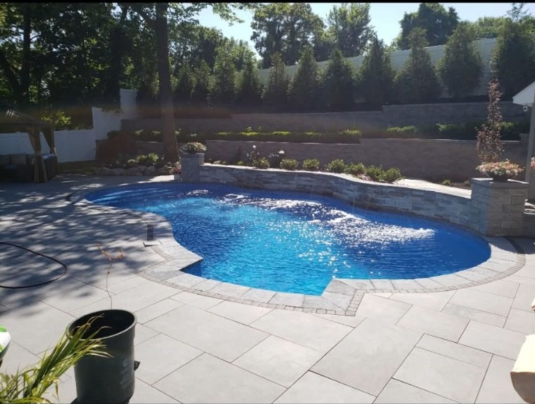 Curved pool surrounded by a stone patio